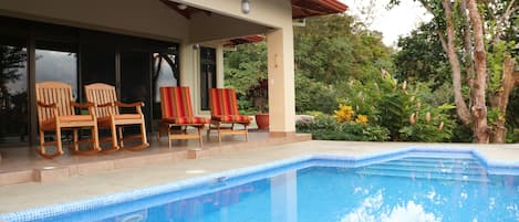 Pool with covered patio. Rocking chairs and chaise  lounges