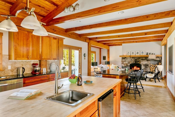 Open kitchen that leads to a living area with fireplace.
