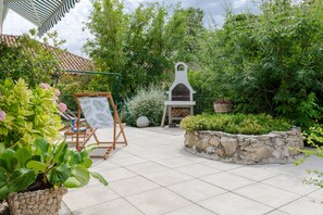 Terrace with a sitting area, garden and outdoor fireplace/grill.