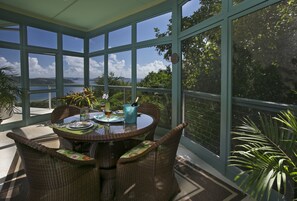 Dining porch secluded in a tropical jungle of palms, completely screened in.