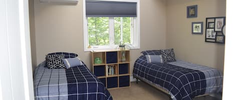 Upstairs bedroom with three single beds, looks out over woods and running creek