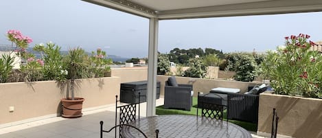 Terrasse vue mer, coin repas sous la pergola et salon de jardin