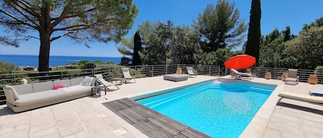 vue de la mer depuis la piscine avec tout le mobilier pour en profiter 