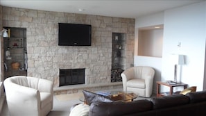 Living area on main level with new stone wall around fireplace & flat-screen TV.