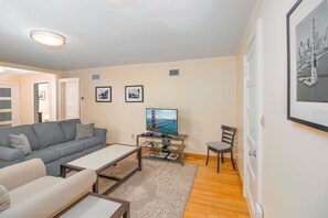 Living room has queen sofabed, sitting chair, coffee table, 2 side tables and TV