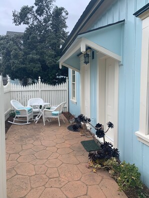 Interior of courtyard patio. Rocking chair, two standard chairs, side table.
