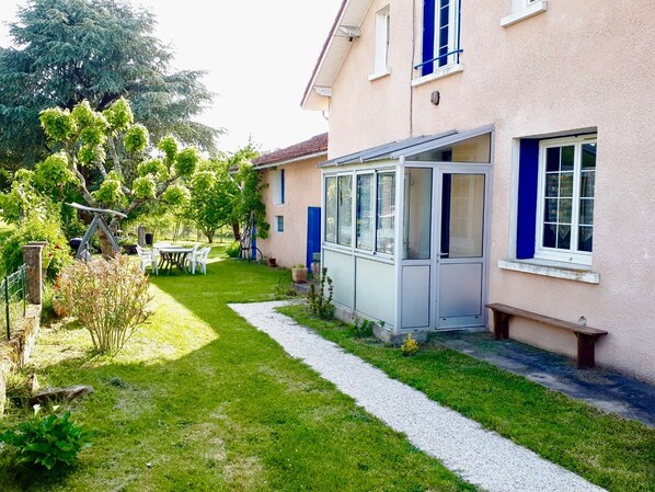 La maison aux volets bleus et son entrée par la véranda 