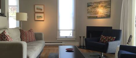 Living room with fireplace and vaulted ceiling, with access to the front patio.