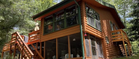 Lakeside view of cabin showing upper and lower screened in porches and deck.