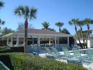Gazebo by the pool with tables/chairs and grill. 