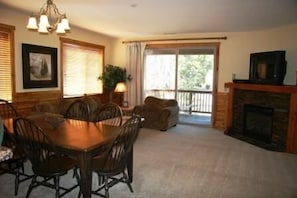 Large, bright living room with gas fireplace, door to deck
