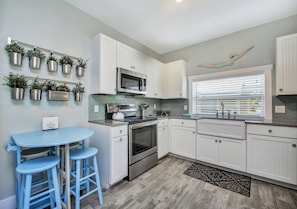 Open kitchen with farmhouse sink, quartz counter tops and glass tile backsplash