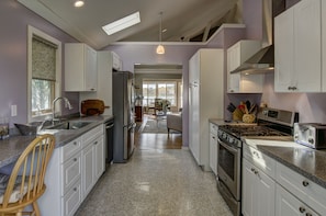 Modern fully equipped kitchen opens into living  room, dining area and deck