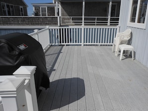 The home  has a large deck with chairs and grill