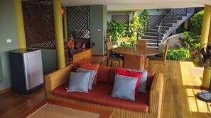 Spacious open living area with wicker seating, dining table & small refrigerator