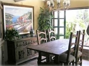 Dining room with view of ocean and lushly landscaped patio