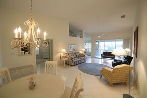 Light high ceiling open plan dining area and living room with access to lanai.