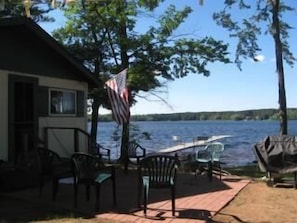 View of dock extending into lake. Patio, grill, fire ring, picnic table, seating