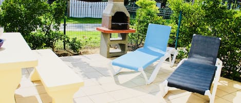 La terrasse avec son barbecue, ses transats et son salon de jardin