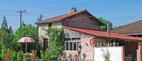 Vue de la façade (côté EST) avec la terrasse extérieure et le patio couvert