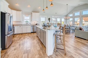 Meal prep is enjoyable in the open kitchen featuring modern, stainless steel appliances including gas stove and French door refrigerator, and a prep sink at the breakfast bar.