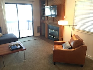 Cozy leather club chair next to gas fireplace and HDTV