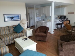 View of family room in foreground, wet bar and kitchen beyond, dining room right