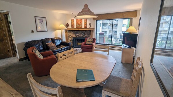 Living room with sofa bed, wood fireplace, dining table, and balcony w/ gas BBQ