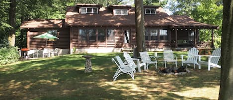 Lake side view of log house. Covered porch, open patio.