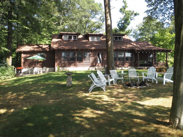 Lake side view of log house. Covered porch, open patio.