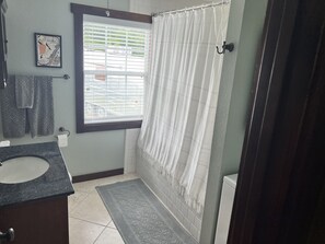 Bathroom with tub and shower, stackable washer and dryer.
