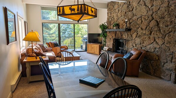 Living room with wood fireplace, dining table, and  balcony with gas BBQ