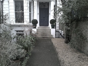 Approaching the front door with the apartment bay window to the left.