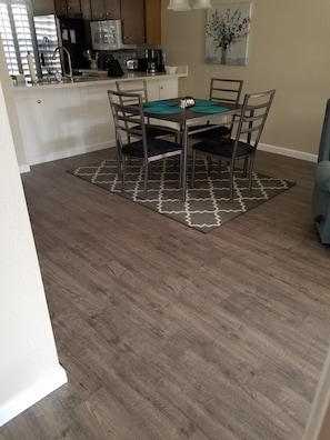 Open dining table to living room.  Pots, pans, silverware, coffee pot, toaster