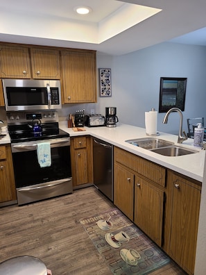 Kitchen with white quartz counters looks into eating area and living room.