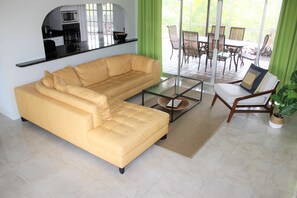 Comfortable living room with Natuzzi leather sofa & view of lanai & greenery.