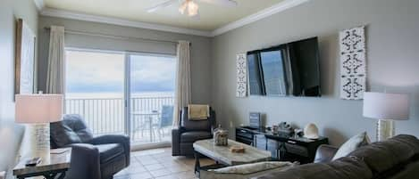 Living area features sliding glass doors leading to balcony with beach front views.