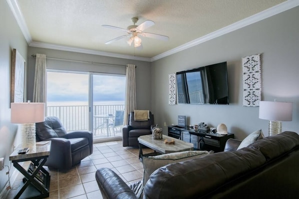 Living area features sliding glass doors leading to balcony with beach front views.