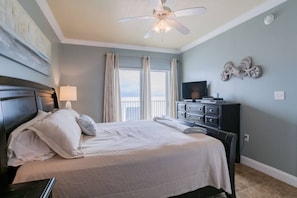 Master bedroom features sliding glass doors leading to balcony with beach front views. This room is furnished with a king-sized bed, dresser, two nightstands, TV, closet, and access to full bathroom..