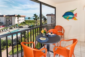 Bright and cheery orange furniture on lanai overlooking pool and beach.