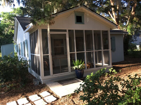 Comfortable screen porch with ceiling fan and two comfortable chairs.