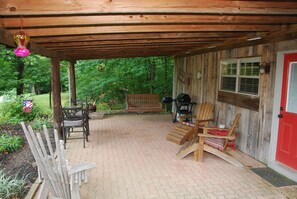 View of covered patio with swing, gas & charcoal grills, and multiple seating.