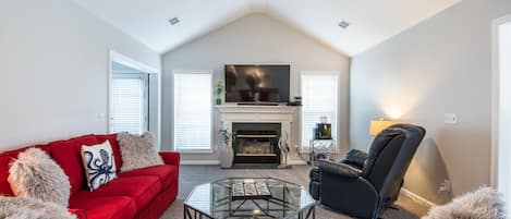 Living room with large flat screen tv, recliner and two couches and ceiling fan.