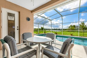 Sheltered lanai has a table, chairs and cooling fan