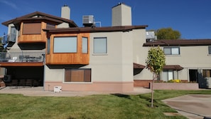 Back of home. Large lawn area, deck, patio, cemented b-ball/game area
