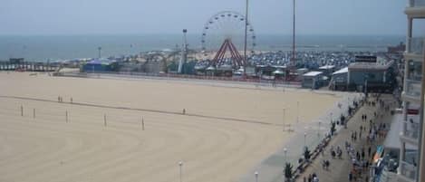 Balcony view of Ocean City boardwalk, beach, ocean, & amusement rides.