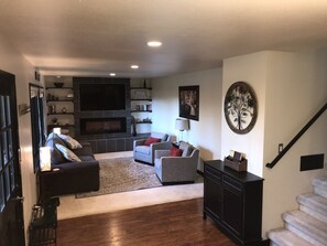 Newly furnished living room with queen sleeper, fireplace, and TV and movies