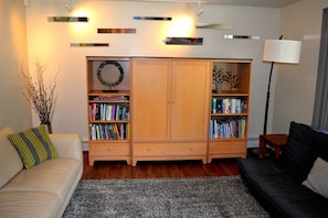 Living room with books for all ages, including an Alaska section, & a hidden TV