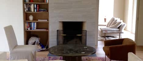 Living room has dramatic fireplace in double-height room. 