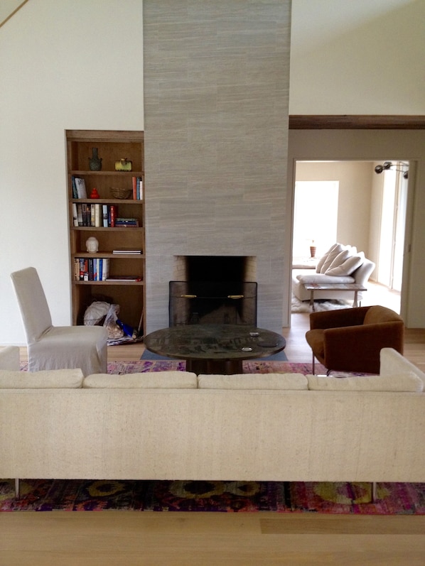 Living room has dramatic fireplace in double-height room. 